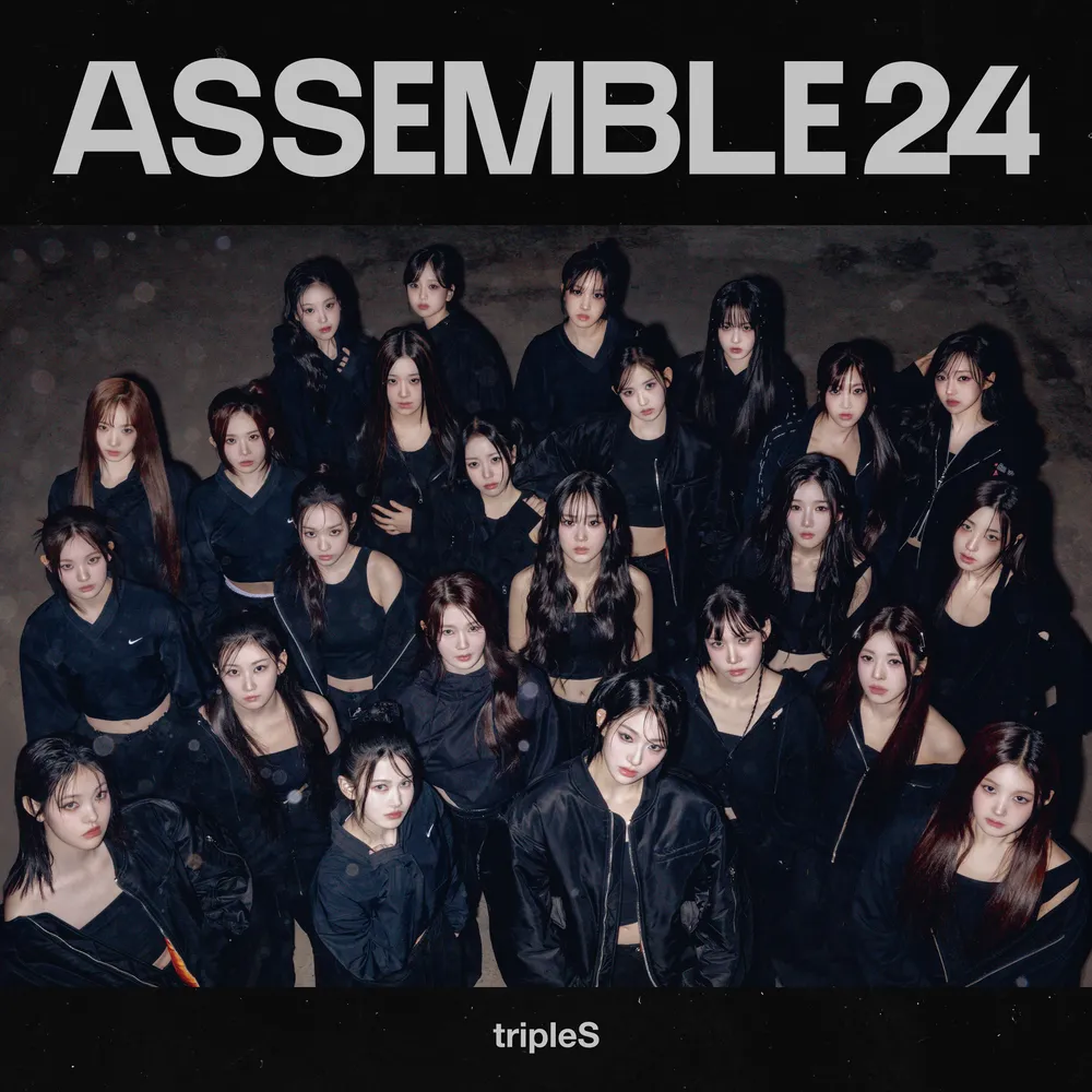 tripleS 24‑member K‑pop girl group standing together in coordinated black outfits under the ‘ASSEMBLE 24’ concept banner, showcasing the full lineup for the group introduction.